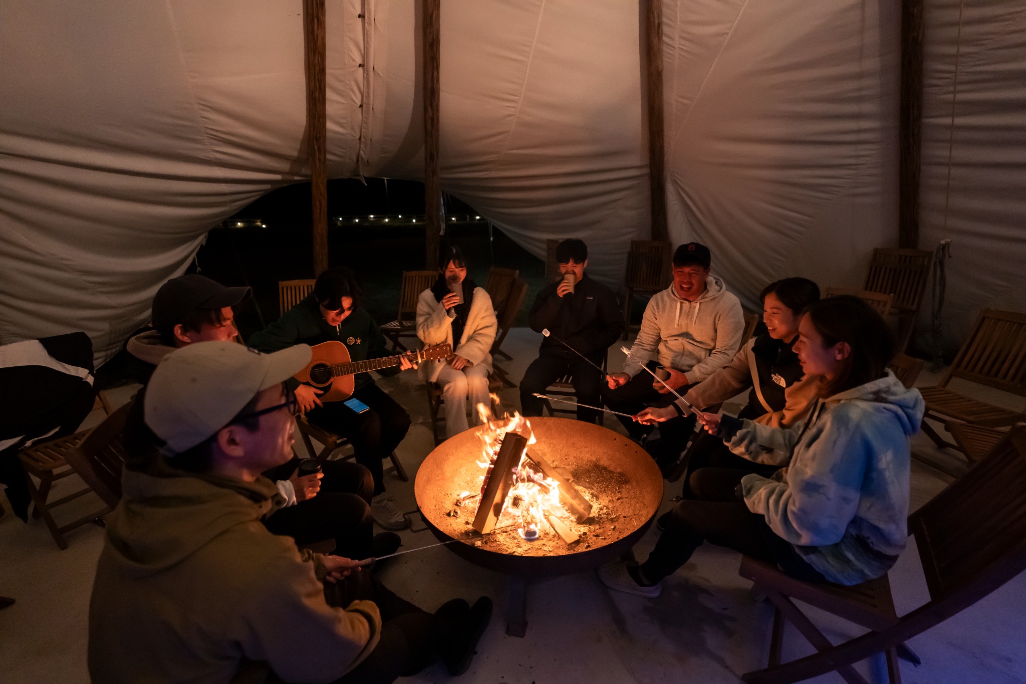 Night-time interior of the Karadomari tipi with guests gathered in warm low light